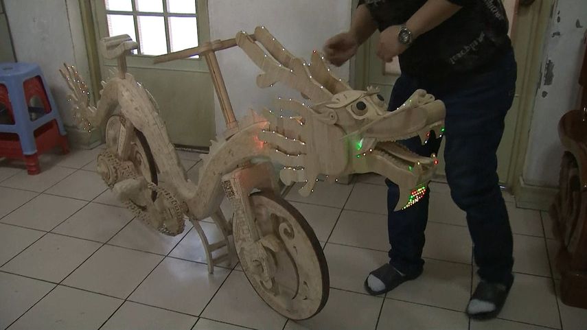 Vista de la bicicleta con forma de dragón fabricada por un chino con palitos de helados.