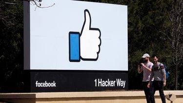 Dos hombres caminan junto a un icono de&nbsp;Facebook&nbsp;en Menlo Park, California, el 30 de marzo del 2018.&nbsp;