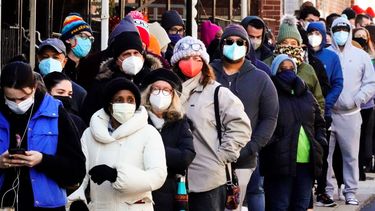 Decenas de residentes de la ciudad hacen una fila que se extiende alrededor de la cuadra para recibir kits gratuitos de prueba rápida de COVID-19 en el hogar.