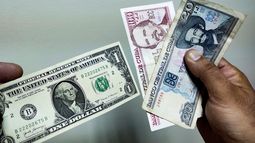 Un hombre muestra un dólar y pesos cubanos en La Habana.
