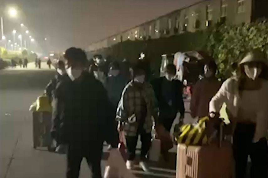 En esta imagen extraída de un video y publicada por Hangpai Xingyang, gente con maletas sale de un complejo de Foxconn en Zhengzhou, en la provincia central china de Henan, el sábado 29 de octubre de 2022. Los trabajadores en una planta de Foxconn en laciudad central china de Zhengzhou parecían haber abandonado el recinto para evitar restricciones asociadas al COVID-19.&nbsp;