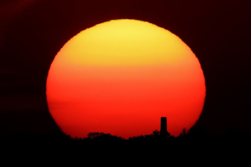 En esta fotografía de archivo del viernes 26 de junio de 2020, se ve a la distancia la puesta del sol atrás de una chimenea en Kansas City, Missouri.&nbsp;