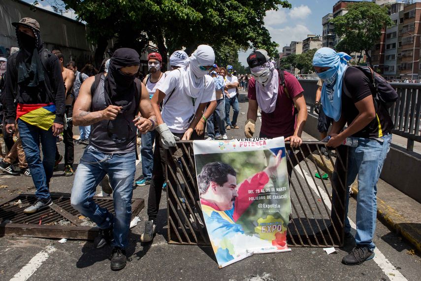 Manifestantes toman un afiche del Presidente Nicolas Maduro para protestar.&nbsp;