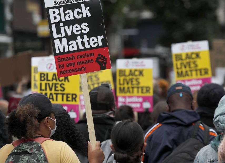 En imagen de archivo del domingo 23 de agosto de 2020, manifestantes del movimiento Black Lives Matter sostiene carteles durante la Marcha del Millón de Personas por el centro de Londres. 