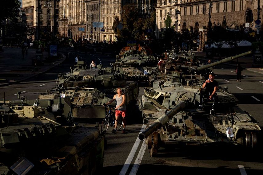 Varias personas caminan entre vehículos militares rusos destruidos instalados en el centro de Kiev, Ucrania, el 24 de agosto de 2022.