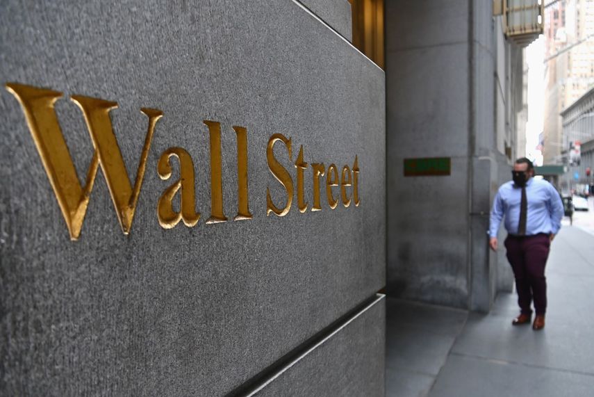 Un hombre camina cerca de la entrada principal de Wall Street.