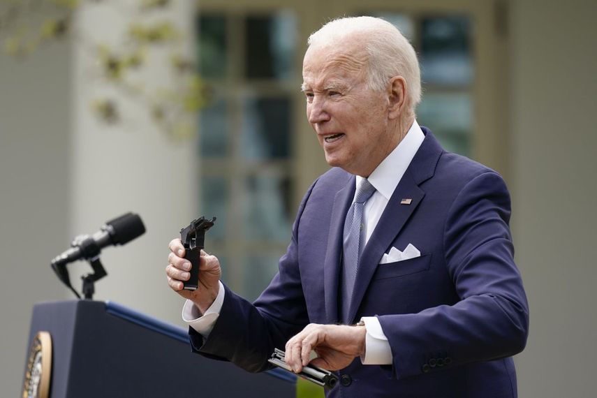 El presidente Joe Biden sostiene piezas de una pistola de 9 mm mientras habla en el jardín de rosas de la Casa Blanca en Washington, donde habló sobre el control de armas, el lunes 11 de abril de 2022.