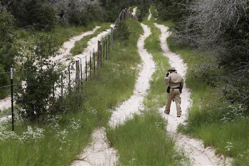 Un agente de la división aérea y marina de la Policía de Aduanas y Protección Fronteriza busca rastros junto a un camino mientras patrulla la frontera de Texas con México  ( Foto AP)