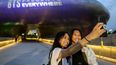 Una madre y su hija se toman una selfie frente a Dongdaemun Design Plaza mientras se ilumina con luz púrpura para conmemorar el décimo aniversario de las megaestrellas del K-pop BTS, en Seúl, Corea del Sur, el 12 de junio de 2023.