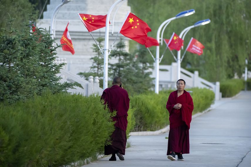 Dos monejes tibetanos caminan por una avenida.