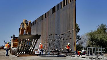 Con la ayuda a una gr&uacute;a gigantesca, trabajadores instalan secciones de un muro pensado para frenar el cruce ilegal de inmigrantes en la frontera&nbsp;