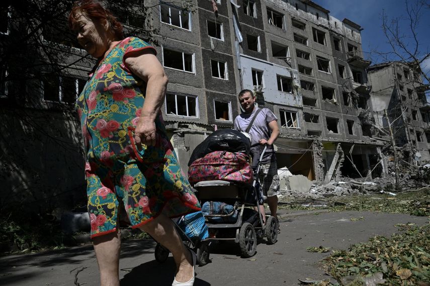 Foto de ucranianos frente a un edificio bombardeado por los rusos en la region del Donetsk.