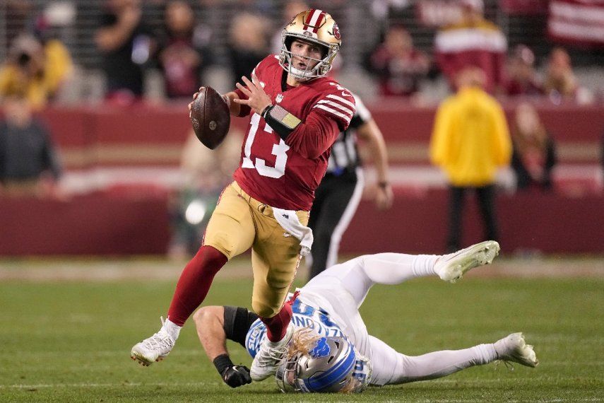 El quarterback Brock Purdy (13), de los 49ers de San Francisco, corre en contra de los Lions de Detroit, superando al linebacker Alex Anzalone, durante la segunda mitad del Juego de Campeonato de la NFC, en Santa Clara, California, el domingo 18 de enero de 2024.&nbsp;