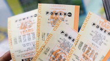 Un cliente sostiene billetes de la lotería Powerball con un premio mayor de $750 millones en la licorería Bluebird, que ha vendido billetes ganadores en anteriores premios de lotería, en Hawthorne, California, el 25 de agosto de 2025. (Foto de Patrick T. Fallon / AFP)
