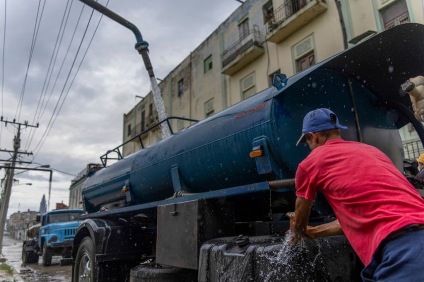 Un conductor de camión cisterna se lava las manos mientras rellena su camión con agua para transportarla a los edificios en medio de la escasez de agua en La Habana, Cuba.