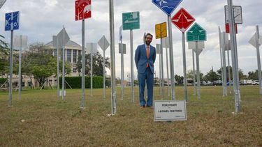 Leonel Matheu, junto a la exhibición Arte Urbano Pedestriart, que consiste en aparentes señales de tráfico emplazadas frente a la alcaldía de Doral.