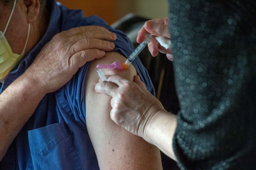 Empleada de la salud vacuna a una persona de la tercera edad.