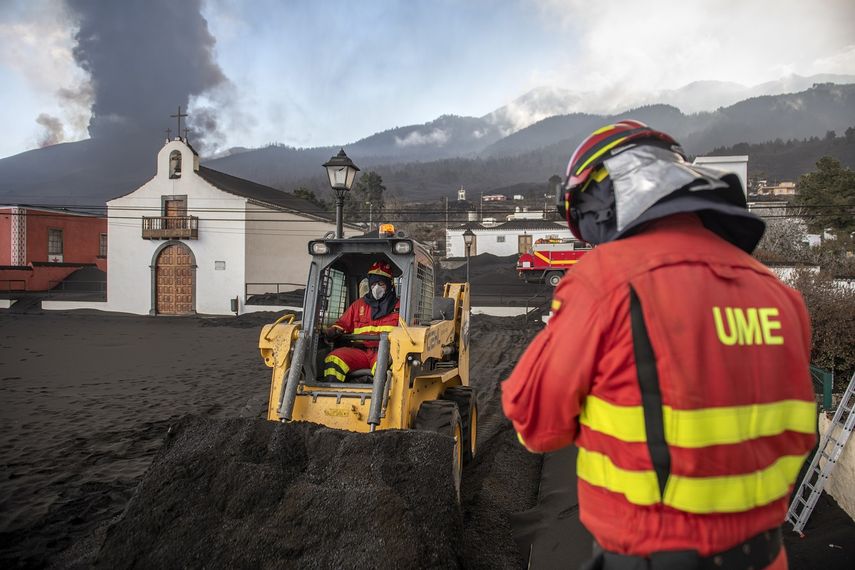 Efectivos de la Unidad Militar de Emergencias (UME) limpian la ceniza volcánica mientras continúa la erupción del volcán de La Palma (detrás de la iglesia), en la isla canaria de La Palma, España, el 13 de octubre de 2021.&nbsp;
