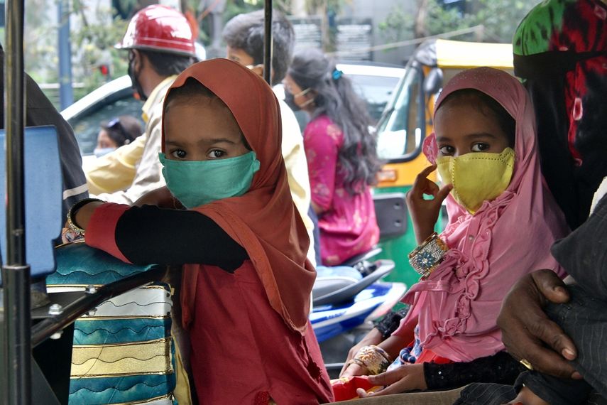 Los niños que viajan con sus padres en un auto rickshaw usan una máscara facial como medida preventiva contra el coronavirus COVID-19, en Bangalore, el 27 de julio de 2020.