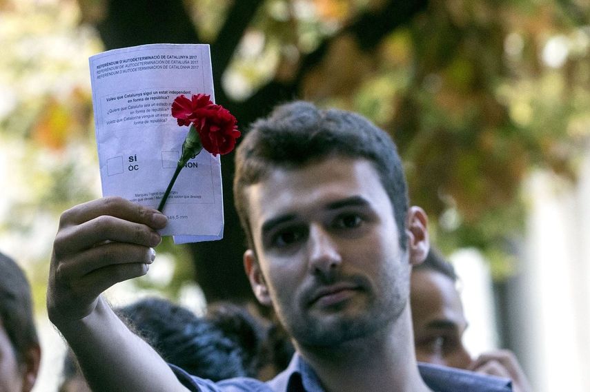 Un joven muestra una papeleta del referéndum durante la concentración ante la consellería de Economía, en la que se protesta por los registros que la Guardia Civil está realizando para recabar indicios relacionados con el referéndum del 1-O, suspendido por el Tribunal Constitucional.&nbsp;
