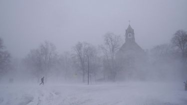Un peatón con equipo para la nieve avanza por el Colonial Circle, con la silueta de la iglesia episcopaliana de St. Johns Grace entre la ventisca, en Buffalo, Nueva York, el sábado 24 de diciembre de 2022.&nbsp;