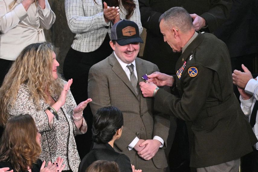 El sargento de la Guardia Nacional Andrew Wolfe (centro, con sombrero), quien sobrevivió a un tiroteo en noviembre de 2025 en Washington, D. C., recibe un Corazón Púrpura al ser reconocido por el presidente de Estados Unidos, Donald Trump, durante su discurso sobre el Estado de la Unión en la Cámara de Representantes del Capitolio de Estados Unidos en Washington, D. C., el 24 de febrero de 2026. 