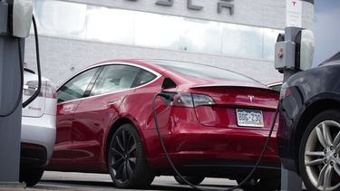 Un auto fabricado por Tesla recarga sus baterías en una estación de servicio.