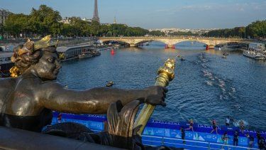 En foto del jueves 17 de agosto del 2023, atletas saltan y nadan en el Río Sena cerca del puente Alexander III en la primera etapa del evento de prueba del triatlón para los Juegos Olímpicos 2024.