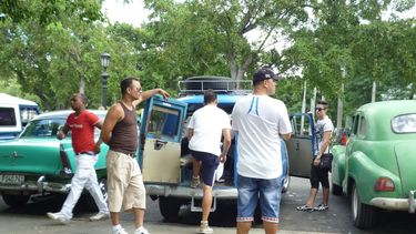 Vista de un grupo de boteros junto a sus autos en un parque de La Habana.