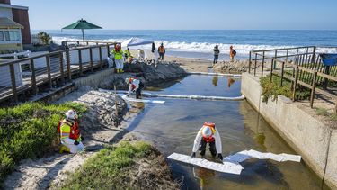 Equipos de limpieza utilizan material absorbente para retirar petróleo que pudiera haber ingresado a un pequeño riachuelo que desemboca en el océano, luego de una fuga en un oleoducto, el jueves 14 de octubre de 2021, en Laguna Beach, California.&nbsp;