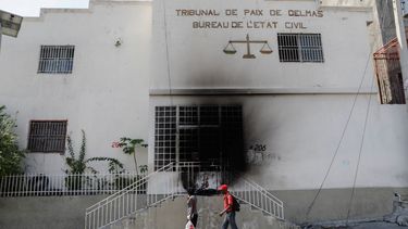 Dos peatones pasan junto a un edificio judicial que fue incendiado por pandillas en el barrio Delmas 28 de Puerto Príncipe, Haití, el 6 de marzo de 2024.&nbsp;