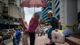 Una señora sale de la sede de la Cruz Roja en Caracas con un kit de agua potable.