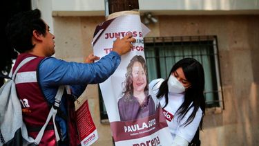 Simpatizantes de la candidata a la alcaldía del partido gobernante Morena, Paula Soto, colocan un cartel en un poste eléctrico en el último día de campaña previo a las elecciones intermedias del 6 de junio, en la Ciudad de México, el sábado 29 de mayo de 2021.