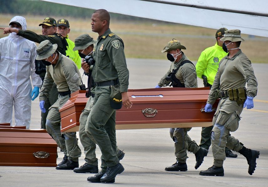 Personal de la Policía ayuda este viernes 22 de junio de 2018, en Cali, Colombia, a cargar los ataúdes con cuatro cuerpos hallados por las autoridades en una zona selvática en el suroeste del país.