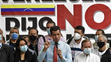 El líder de la oposición venezolana Juan Guaidó (C) hace gestos mientras habla durante una conferencia de prensa frente a un cartel que dice “Venezuela dijo no al fraude”, en el que anunció el lanzamiento de una consulta popular virtual para ignorar las últimas elecciones legislativas en Caracas. el 7 de diciembre de 2020.