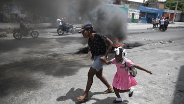 Una mujer y una niña corren junto a una fogata durante una manifestación contra la violencia en Puerto Príncipe, Haití, el 29 de marzo del 2022.&nbsp;