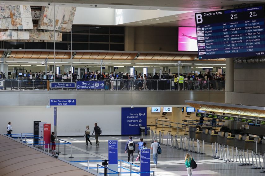 Agentes de la TSA inspeccionan a los pasajeros mientras estos esperan el control de seguridad en un puesto de la Administración de Seguridad del Transporte (TSA) dentro de la Terminal Internacional Tom Bradley (TBIT) del Aeropuerto Internacional de Los Ángeles (LAX), en Los Ángeles, California, el 23 de marzo de 2026.