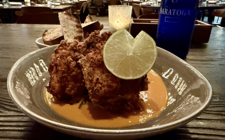 Pollo frito coreano, servido con mantequilla de chile y espinacas.