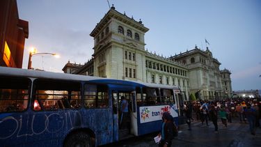 Manifestantes se acercan a un autobús dañado por manifestantes frente al Palacio Nacional para exigir la renuncia del presidente Alejandro Giammattei, en la Ciudad de Guatemala, el sábado 28 de noviembre de 2020.