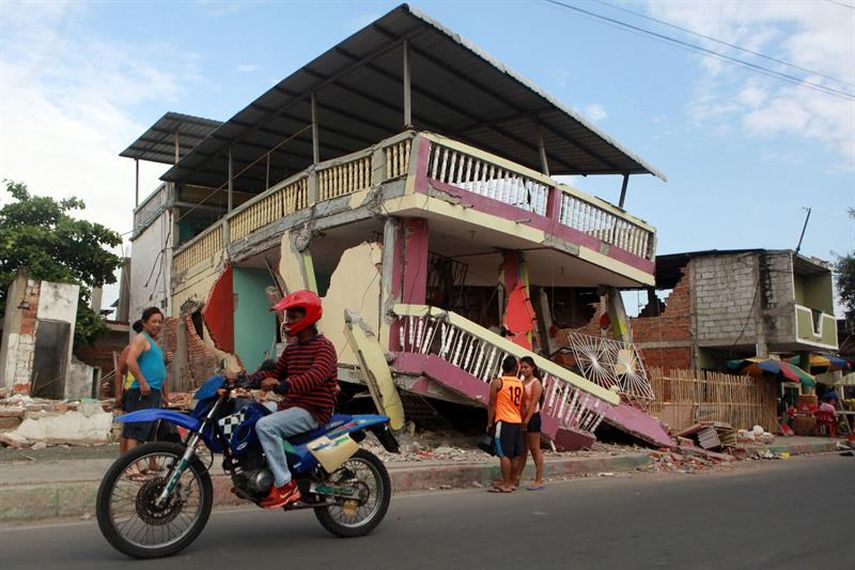 Habitantes cruzan frente a una vivienda averiada por el terremoto en Manta, Ecuador. Una semana después del sismo fatal, los ciudadanos se debaten entre el miedo que les producen las réplicas y el deseo de volver a la normalidad. (EFE)