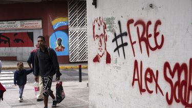 La gente camina cerca de un grafiti exigiendo la libertad del empresario colombiano Alex Saab, en el oeste de Caracas, el 23 de febrero de 2021.&nbsp;&nbsp;