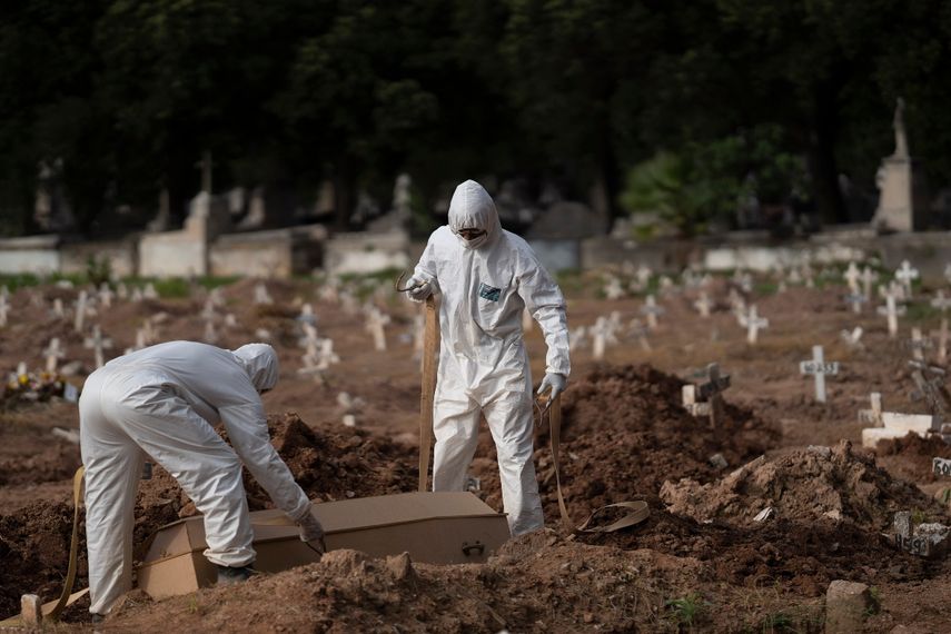 Trabajadores de un cementerio con trajes de protección colocan el ataúd de Paulo Jose da Silva, de 57 años, que murió por el nuevo coronavirus, en Río de Janeiro, Brasil, el viernes 5 de junio de 2020. Según Monique dos Santos, su padrastro se burlaba de la existencia del virus, no llevaba mascarilla, no se cuidaba y quería estrechar la mano con todo el mundo. No creía en ello y por desgracia encontró su fin. Es muy triste, pero es la verdad, dijo.&nbsp;