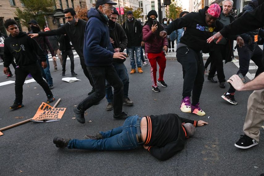 Un partidario del presidente de los Estados Unidos, Donald Trump, tirado en el suelo, recibe un puntapié cuando es atacado por manifestantes anti-Trump en Black Lives Matter Plaza en Washington, DC el 14 de noviembre de 2020.