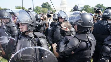 Varios policías rodean a un hombre (al centro, con anteojos) durante un mitin cerca del Capitolio de Estados Unidos el sábado 18 de septiembre de 2021, en Washington, D.C.