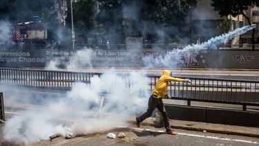 Un manifestantes devuelve una bombas lacrimógena a la Policía Nacional Bolivariana durante la reyerta de este sábado en la avenida Libertador.&nbsp;