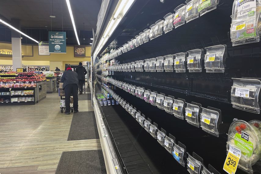 Unas personas caminan por pasillos con estantes vacíos en una tienda de Safeway, el martes 11 de enero de 2022, en Washington.&nbsp;