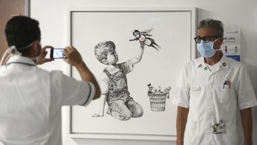 Un miembro del personal se toma una foto junto a una nueva obra de Banksy titulada Game Changer, expuesta para los trabajadores y pacientes del Hospital General de Southampton en Inglaterra el jueves siete de mayo del 2020.&nbsp;