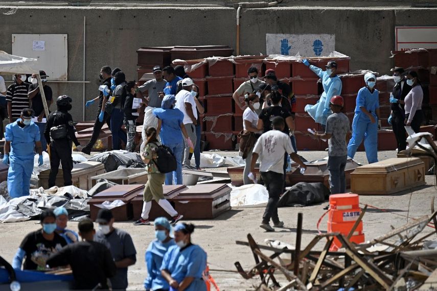Expertos forenses llevan a cabo labores de identificación de cadáveres dispuestos en el suelo, cerca de ataúdes, en una morgue improvisada en el puerto de La Guaira (estado de La Guaira, Venezuela) el 29 de junio de 2026, días después de que dos terremotos sacudieran el país.