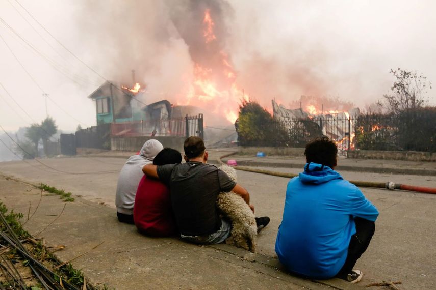 Una familia observa cómo las llamas devoran su residencia en Penco, Chile.