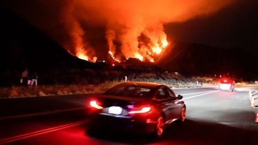   Conductores se abren paso en una carretera en una zona de incendios, el jueves 13 de agosto de 2020, en Azusa, California.